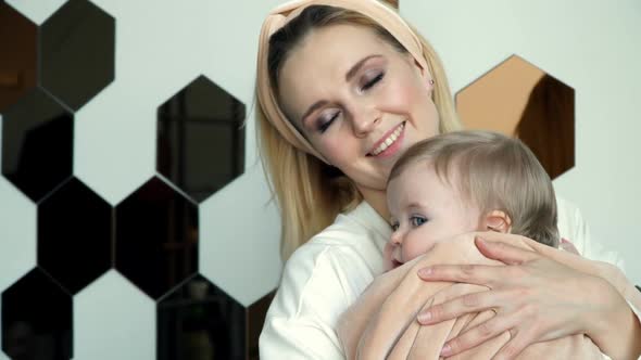 Young Mother Dandles Baby in Arms and Sings Lullaby to Little Cute Daughter Swaddling Plush Plaid alt