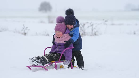 Happy children play with sledges in a beautiful winter park.