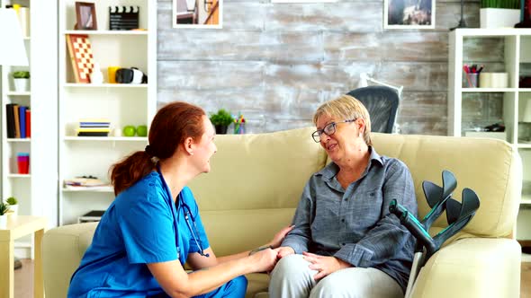 Female Nurse Holding Old Woman Hand in Nursing Home alt