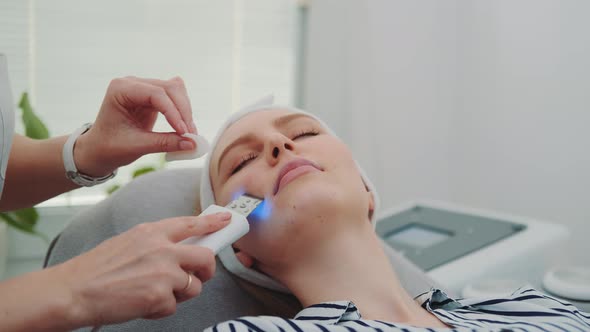 Close-up Shot of Professional Cosmetologist Making Cavitation Peeling on Young Woman's Face alt