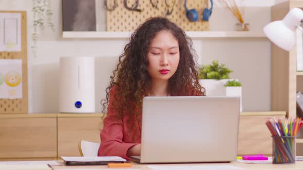 Asian Businesswoman working on laptop computer at home office.  Professional typing on laptop keyboa alt