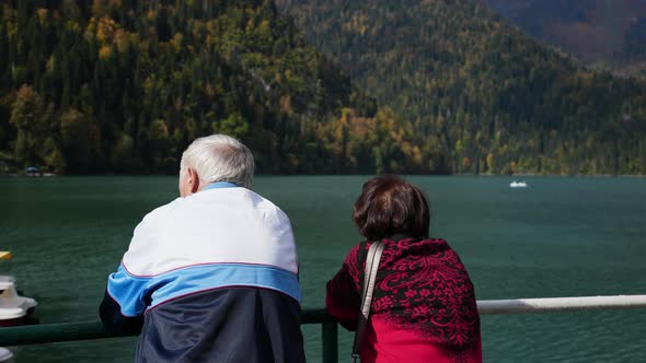 Family of Old Travelers Watching Sailing Boats on Windy Mountain Lake Together alt