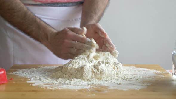 Man pouring water in flour preparing pizza dough