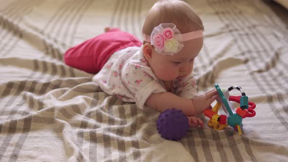 Cute Baby Girl Playing with Toy Ball on Floor