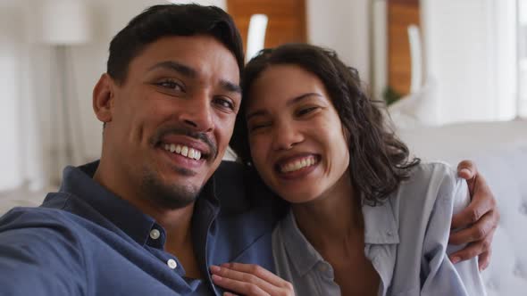 Portrait of happy hispanic couple embracing on sofa in living room alt