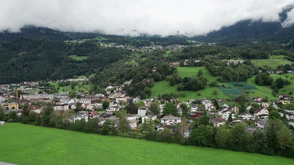 Liechtenstein with Houses on Green Fields in Alps Mountain Valley Aerial View alt
