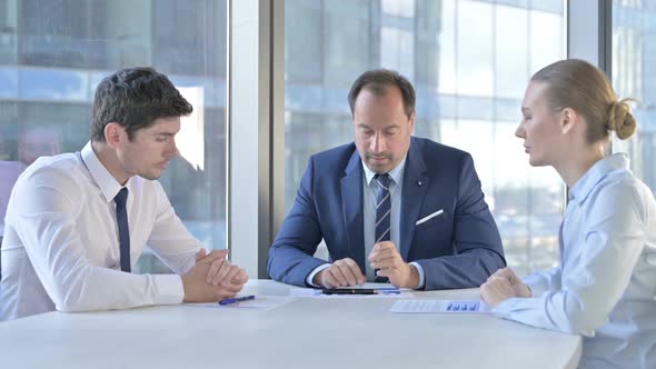 Middle Aged Businessman Having Talk on Documents with Assistants on Office Table alt