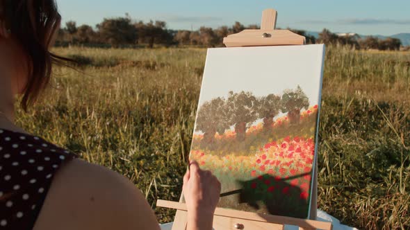 Young girl paints the picture on canvas in the countryside alt