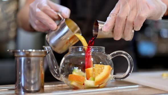 Crop Barista Pouring Orange Juice and Wine Into Teapot