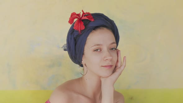 Portrait of Caucasian Woman Wearing Blue Turban with Flowers on Light Yellow Background. Smiling alt