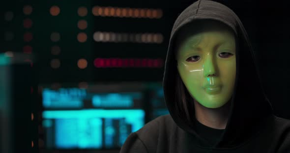 Dangerous Internationally Wanted Hacker with Masked Face Speaks Into the Camera In the Background alt