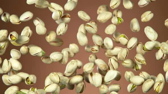 Super Slow Motion Shot of Flying Pistachios After Being Exploded on Brown Background at 1000Fps alt