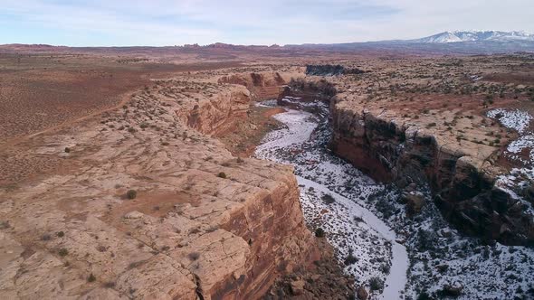 Rising aerial view of canyon cutting through the desert landscape alt