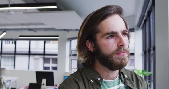 Caucasian businessman standing looking out of a window in modern office alt