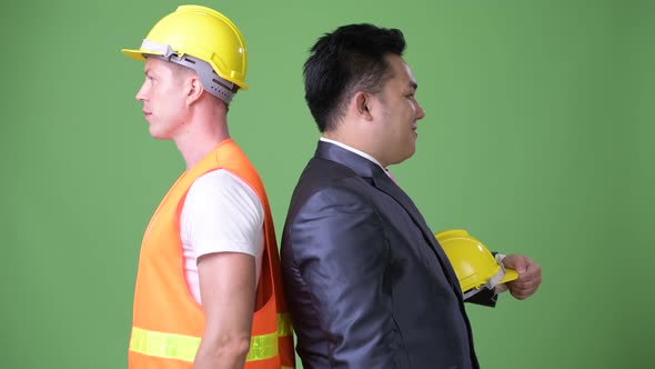Scandinavian Man Construction Worker and Asian Businessman Working Together alt