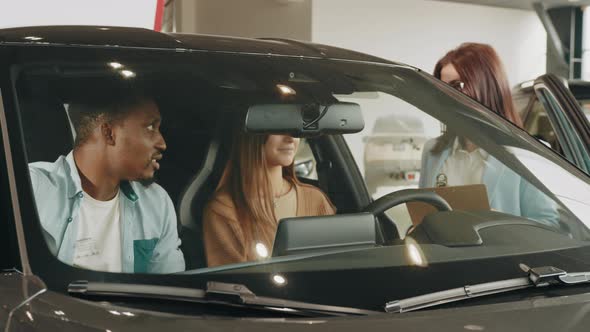 Female Seller Working with Multiracial Couple at Modern Auto Center alt