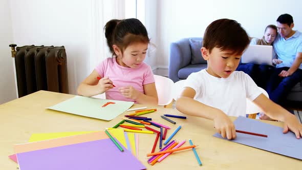 Children doing homework while parents relaxing on sofa alt
