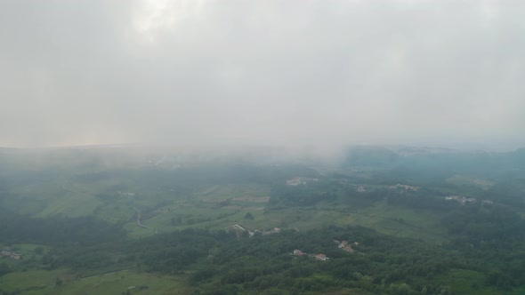 Aerial drone shot of lands with fog and clouds in Italy