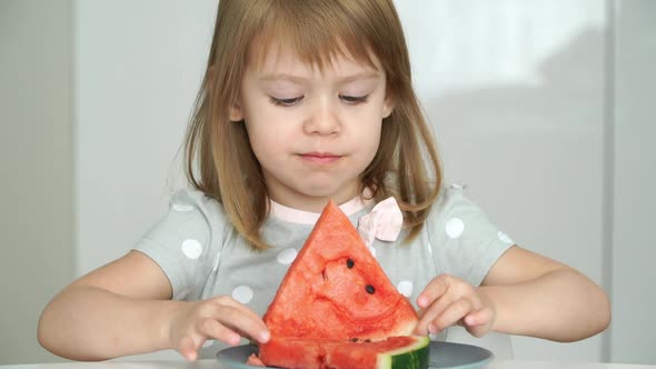 Portrait of Little 3 Year Old Child Girl Looks at Camera and Eats with Appetite Red Ripe Juicy