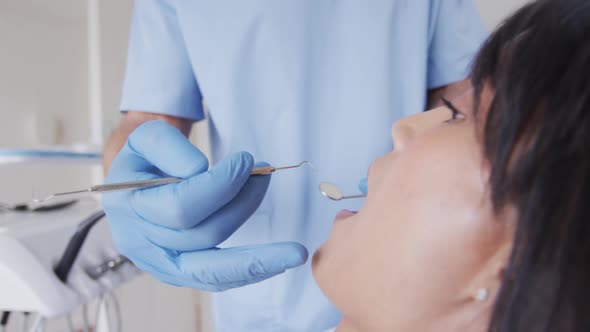 Caucasian male dentist examining teeth of female patient at modern dental clinic alt