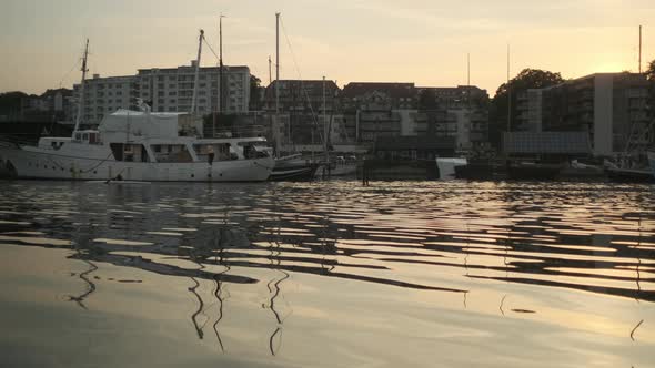 Panning Shot of Boats Docked By the Bay and Houses in Background alt