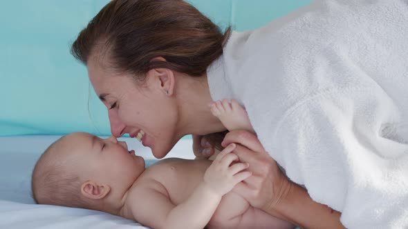 Close Up Shot of Young Mother Is Playing with Her Newborn Baby in a Nursery in a Morning alt