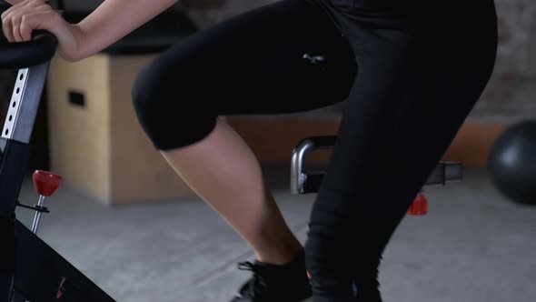 Athletic Indian woman in sportswear riding on exercise bike during cycling class at gym  alt