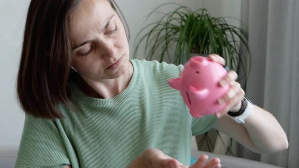 Young Sad Woman is Shaking Empty Piggy Bank