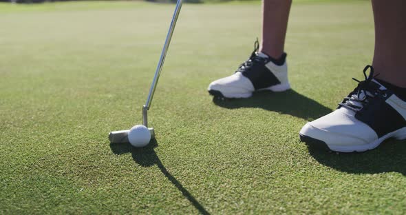 Caucasian female golf player taking shot from bunker standing on golf field alt