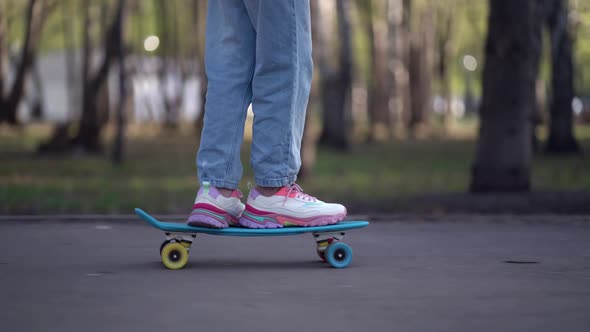 Close Up Legs Riding on Skateboard in Motion of Asphalt in Park