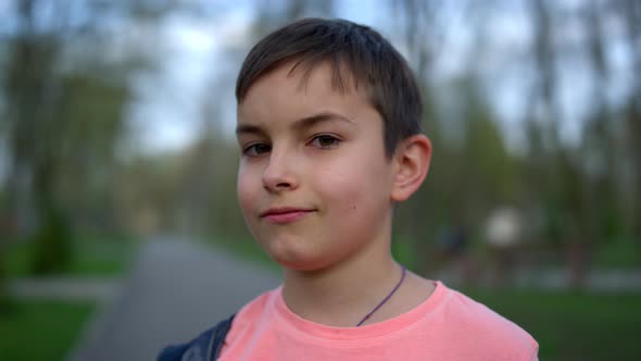 Joyful Teen Boy Looking Camera in Park. Laughing Guy in Brackets Posing Outdoors alt