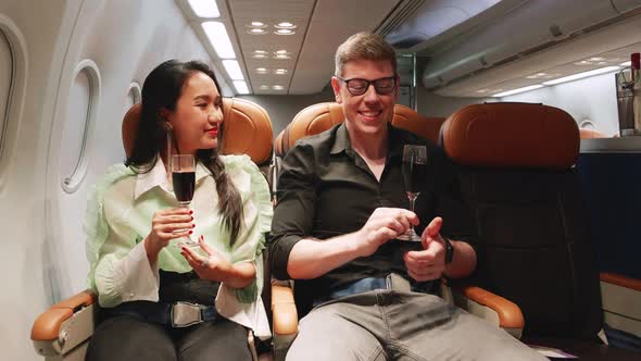 Man and woman holding champagne glasses and cheers while traveling on airplane