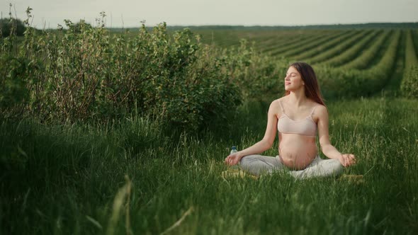 young woman with dark hair in a pink top and light pants enjoys the sun outdoors.  alt