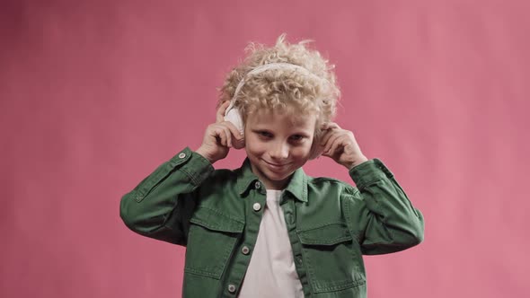 Little Blonde Boy Wearing Big Headphones and Nodding His Head