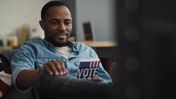 Handheld video of content black man watching TV. Shot with RED helium camera in 8K. alt
