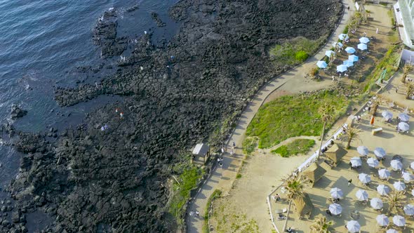 The scenery of a resort with people walking on the Jeju Olle Trail. Jeju Handam Beach.