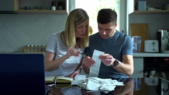 Man and Woman Looking at Payment Bills in the Kitchen alt
