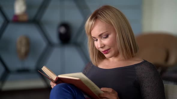 Attractive Adult Woman Is Relaxing at Home, Reading Book, Sitting at Living Room alt