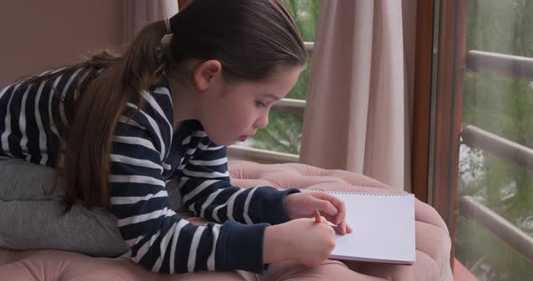 A Little Girl Drawing with Pencils at Home