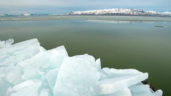 Time lapse looking past ice blocks as sheet of ice floats by in Utah Lake alt