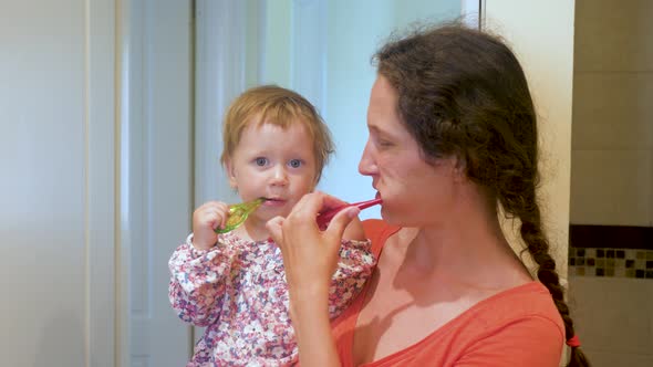 Mother Teaching Kid Teeth Brushing. Mother and Daughter Brushing Teeth Together in Bathroom. Family