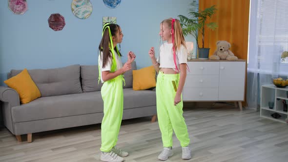 Stylish Girlfriends Learn to Dance at Home Female Children with Bright Pigtails and Similar Clothes alt