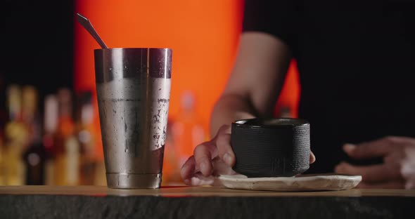 Bartender Puts Big Ice Cube to the Frozed Cocktail Clay Mug By Forceps Making the Cocktail in the alt