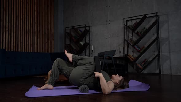 the Woman Put a Towel Roller Under Lower Back Bent Knees and Pulled Left Leg Up to Stomach with a alt