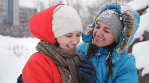 Mother and Daughter Teenager Cuddling and Having Fun in the Winter in the Snow alt