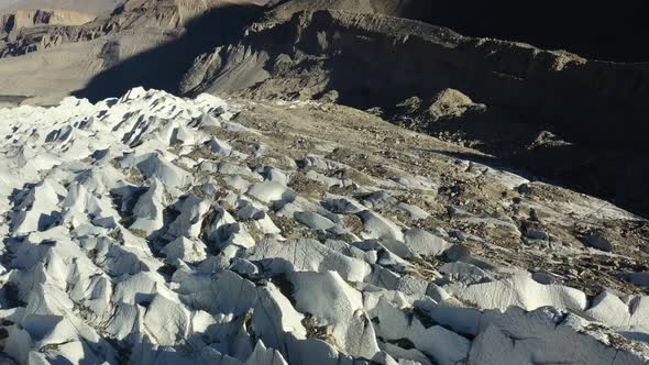 aerial drone flying over the crevasses of Passu Glacier in Hunza Pakistan along with dirt and rock m alt