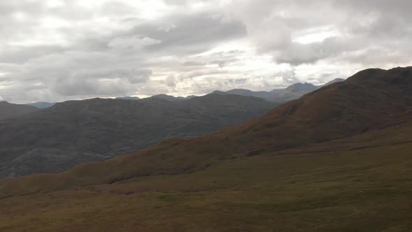 Panoramic drone shot of mountains with green grass in loch lomond national park in scotland. Cloudy alt