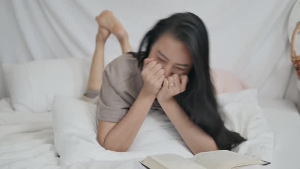 Asian girl reading a book falls in love with her favorite novel as she lies in bed.