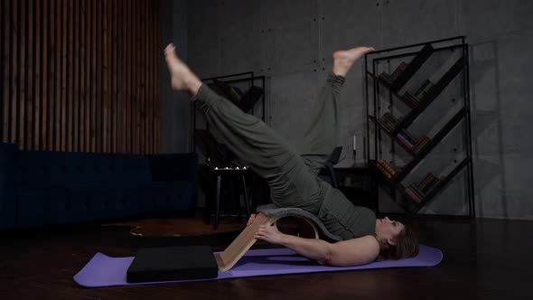 a Woman is Lying on a Sports Mat Against a Gray Wall alt