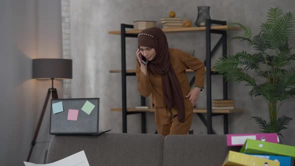 Wide Shot of Serious Confident Professional Middle Eastern Young Woman in Hijab Walking in Living alt